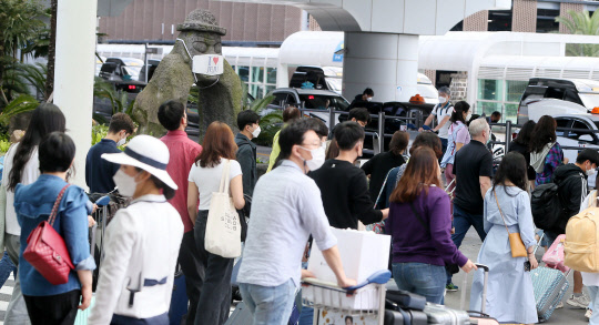 제주로 몰린 관광객… 방역 '비상'  추석연휴를 앞둔 9월 마지막 일요일인 27일 오전 제주국제공항에 도착한 관광객들이 마스크를 쓰고 주차장으로 향하고 있다.  제주=연합뉴스